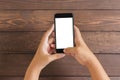 Phone in woman hand showing white screen on wood table Royalty Free Stock Photo