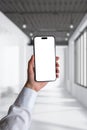 Phone in woman's hand with a white shirt. Business composition in an illuminated white office