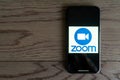Phone on a wooden table or desk showing Zoom Cloud Meetings app.