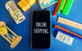Phone with the word Online shopping with money, boxes and hourglass. Purchase of goods and services through the Internet using a