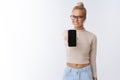 Phone you need. Portrait of attractive friendly-looking pleasant european blond girl showing smartphone screen and Royalty Free Stock Photo