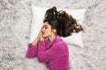 Photo from above of brunette woman wearing girlish housecoat lying and sleeping on white fur in apartment Royalty Free Stock Photo