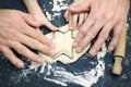 A photo from above of father and child hands cutting the star with a cookie cutter on the wooden table. An overhead photo of fathe Royalty Free Stock Photo