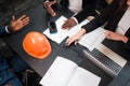 Photo from above. Paper documents laptop and construction helmet with hands of businessmen and office women workers