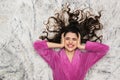 Photo from above of pretty woman wearing girlish housecoat lying on white fur in apartment