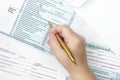 A photo from above of a Tax Form 1040. A woman signing or filling the form. The 1040 income tax form. Top veiw, selective soft foc