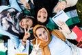 Photo from above of three islamic girls wearing headscarfs lying on blanket in green park Royalty Free Stock Photo