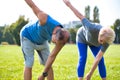 Active flexible senior couple stretching leg in park on sunny day