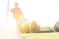 Active senior woman stretching leg in park on sunny day with yellow lens flare in background Royalty Free Stock Photo