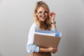 Photo of adorable blond secretary woman wearing eyeglasses smiling and holding file folder while working in office Royalty Free Stock Photo