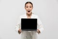 Photo of adorable businesswoman 20s wearing elegant jacket holding laptop and showing black screen Royalty Free Stock Photo