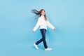Photo of adorable charming student girl wear white sweater smiling walking wind blowing isolated blue color background
