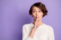 Photo of adorable charming young woman finger lips ask no talks looking empty space isolated purple color background Royalty Free Stock Photo