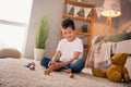Photo of adorable cute boy sitting floor in play room home have free time make words with abc blocks Royalty Free Stock Photo