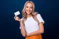 Photo of adorable cute girl wear white clothes hand hold bank card isolated on dark blue color background