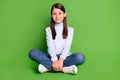 Photo of adorable cute school girl dressed blue turtleneck sitting floor legs crossed smiling isolated green color Royalty Free Stock Photo