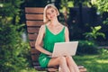 Photo of adorable cute young lady wear green outfit smiling sitting bench writing modern gadget outside urban city