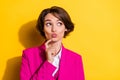 Photo of adorable dreamy young woman dressed pink suit finger pouted lips looking empty space isolated yellow color