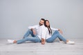 Photo of adorable lady guy wear white shirts sitting floor holding arms isolated concrete grey wall background Royalty Free Stock Photo