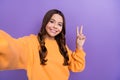 Photo of adorable positive blogger chatting instagram facebook followers v-sign empt space isolated on purple color