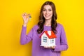 Photo of adorable pretty lady wear violet sweater holding small house keys isolated yellow color background Royalty Free Stock Photo