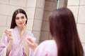 Photo of adorable pretty young woman nightwear pink bathrobe looking mirror applying lip balm indoors house home room Royalty Free Stock Photo