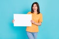 Photo of adorable satisfied impressed girl dressed yellow t-shirt hands hold placard banner isolated on turquoise color