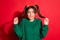 Photo of adorable shy teenager girl wear green knitted pullover hands arms tails looking empty space isolated red color Royalty Free Stock Photo