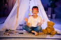 Photo of adorable sweet boy playing native indian game catch bubbles in homemade tent indoors evening playroom Royalty Free Stock Photo