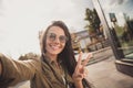 Photo of adorable sweet young lady wear brown shirt dark glasses smiling making selfie showing v-sign outside sunny Royalty Free Stock Photo