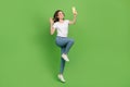 Photo of adorable sweet young lady wear white t-shirt jumping high video talk modern device isolated green color