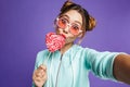 Photo of adorable woman 20s with hair in buns holding big candy Royalty Free Stock Photo