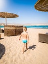 Image of adorable 3 years old little boy walking on the hot beach sand to the sea. Child relaxing and having good time Royalty Free Stock Photo