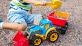 Photo of adorable 3 years old toddler boy playing with sand and you truck and trailer in park. Child digging and Royalty Free Stock Photo