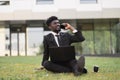 Photo of adult African American man in black business suit sitting on grass in urban park Royalty Free Stock Photo