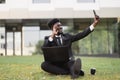 Photo of adult African American man in black business suit sitting on grass in urban park Royalty Free Stock Photo