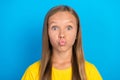 Photo of affectionate small lady pout lips send air kiss wear yellow t-shirt isolated blue color background Royalty Free Stock Photo