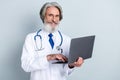 Photo of aged doctor use laptop type prescription eyewear treatment outbreak expert uniform isolated over grey color Royalty Free Stock Photo