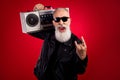 Photo of aged excited man happy positive smile hold boombox show rock sign brutal music lover isolated over red color