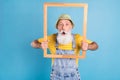 Photo of aged man amazed shocked surprised hold wooden frame photographing isolated over blue color background