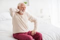 Photo of aged man pensioner sit on bed house indoors unhappy sad upset hand touch shoulders pain spasm ache Royalty Free Stock Photo