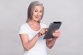 Photo of aged woman happy positive smile look read browse tablet isolated over grey color background