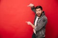 Photo of agitated man wih beard in casual clothing pointing fingers on copyspace text or product with surprise and smile, isolate Royalty Free Stock Photo