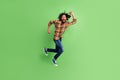 Photo of amazed african guy jump hurry run shout wear plaid shirt jeans green color background