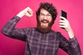 Photo of amazed bearded man with round glasses celebrating success and holding tablet Royalty Free Stock Photo