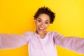 Photo of amazed excited dark skin woman make selfie good mood enjoy isolated on shine yellow color background