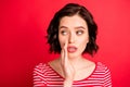 Photo of amazed girl attempting to tell her girl secret as quietly as possible while isolated with red background