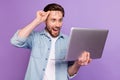 Photo of amazed happy astonished man look laptop take off glasses isolated on purple color background