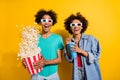 Photo of amazed happy dark skin people couple film glasses pop corn fly drink isolated on yellow color background Royalty Free Stock Photo