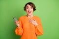 Photo of amazed shocked young woman hold phone reaction like notification isolated on green color background